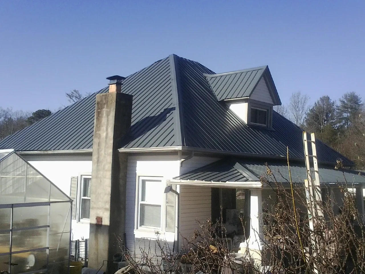 Dark blue standing seam metal roof on a white farmhouse with dormer — Slate & Tile Roof Repair by Roofing Brothers in Jerome