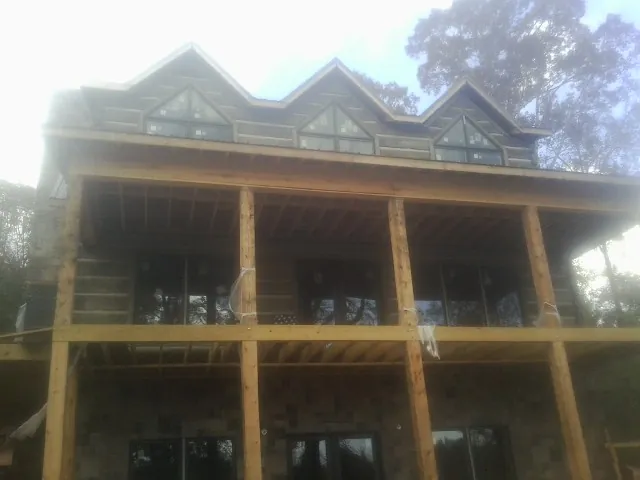 Dormers and porch framing on a large log home under construction — Roof Coating work by our crew in Jerome