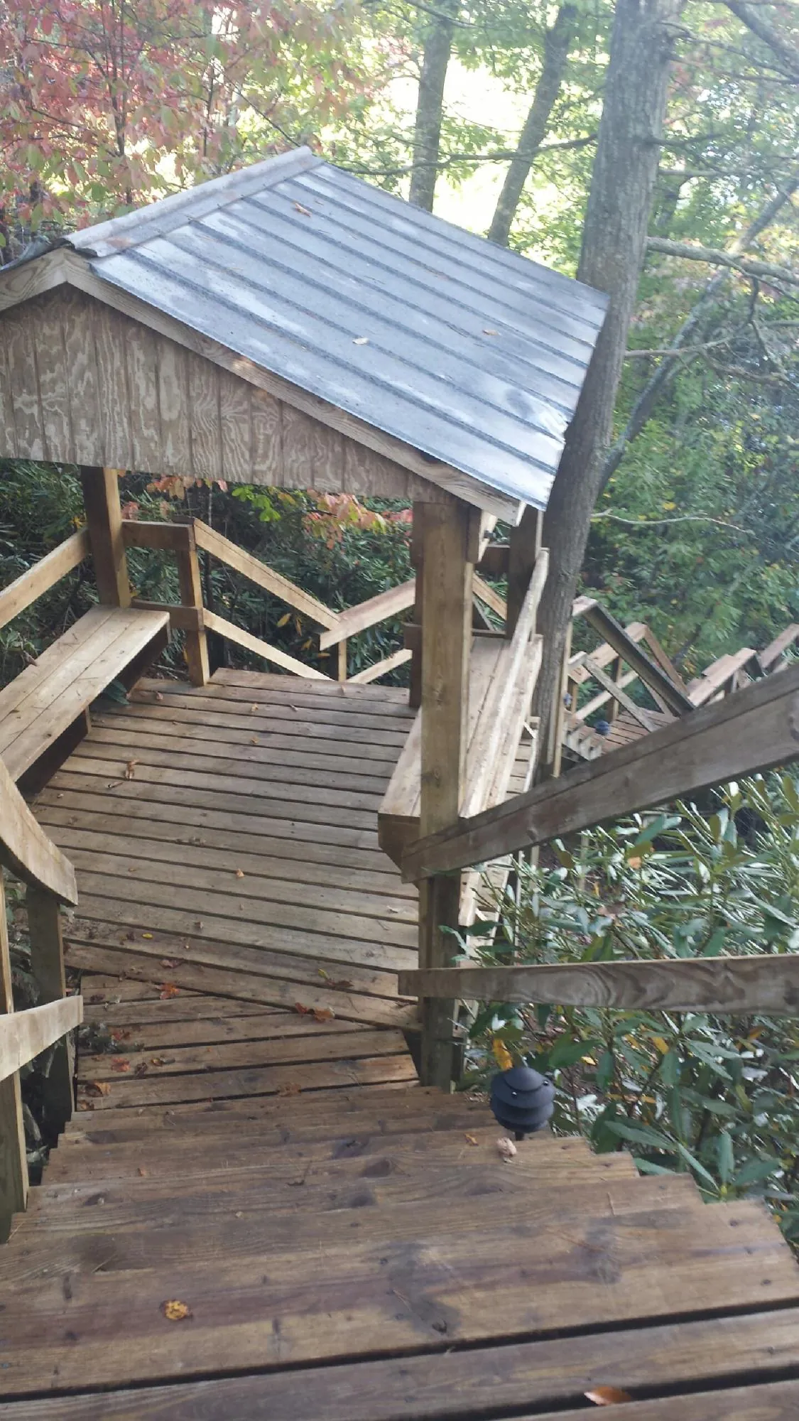 Metal roofed shelter over wooden steps on a wooded walkway — Skylight Repair & Installation work by our crew in Jerome