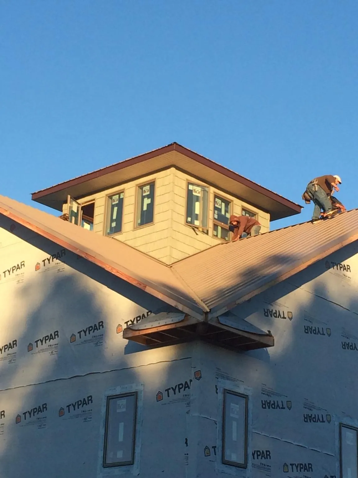 Roofers working around a rooftop cupola on a new metal roof at sunset — Roof Waterproofing in Jerome by Roofing Brothers